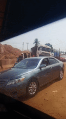 Semi-truck disabled on dirt road, people gather nearby
