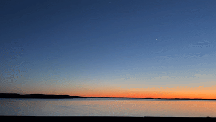 Sunset to moonrise observed over calm water body