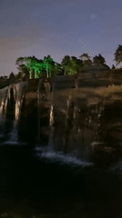 Illuminated park waterfall and modern building at night, Shulgino
