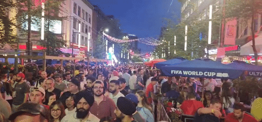 Brazilian street celebration with crowds and illuminated soccer sculptures