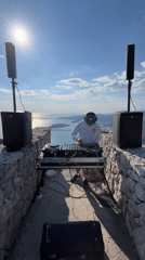 DJ performs on historic stone structure overlooking Montenegro coastline