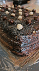 Log-shaped chocolate cake with decorative toppings captured on grey tray