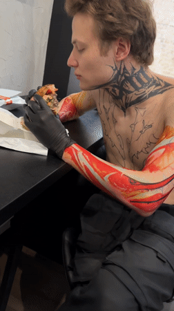 Tattooed man eats burger amid collectibles display in Moscow