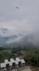 Misty mountain village with white buildings and a winding dirt road