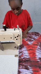 Child operates sewing machine; group walks dirt path