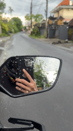 Motorcyclist uses phone during rainy ride in Mengwi
