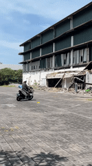 Motorcyclist rides through Kuta parking lot at dawn