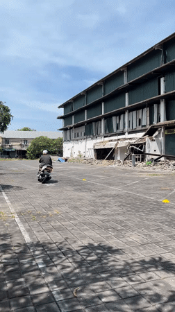 Motorcyclist rides through Kuta parking lot at dawn