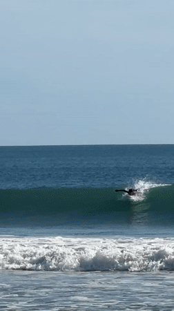 Surfer catches wave at Kuta beach, Indonesia