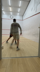 Two men play squash in well-lit indoor court