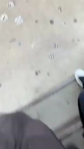 The video shows a first-person perspective of two individuals walking up concrete stairs outdoors. The person recording the video is wearing brown boots and long brown skirt. Another person, wearing white shoes and dark pants, is walking alongside the first person. The stairs are weathered with multiple small holes and some debris. As they ascend, a star-shaped object becomes visible on one of the steps. The overall environment suggests an urban setting with worn, functional architecture.
