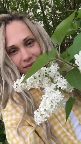 Woman photographed with blooming lilacs in rural Russia