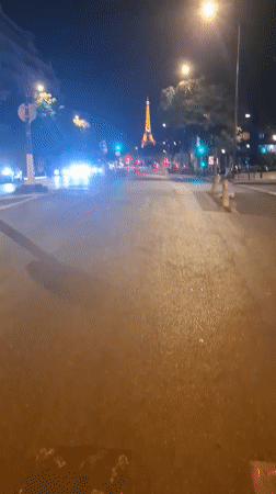 Eiffel Tower lit up behind a busy Paris street at night