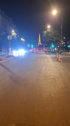 Eiffel Tower lit up behind a busy Paris street at night