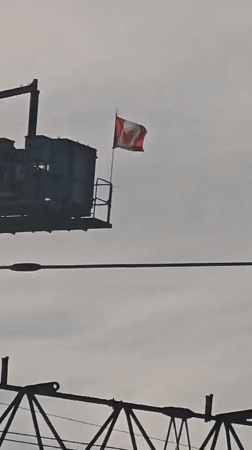 Canadian flag on industrial structure, gray Vancouver skies