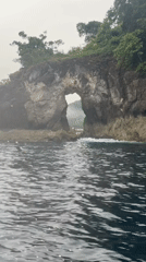Boat approaches natural sea arch near Nusa Penida, Indonesia
