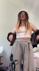 Young woman dances in bedroom wearing white hat in Russia