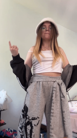 Young woman dances in bedroom wearing white hat in Russia