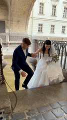 Wedding couple walks cobblestone streets near arched bridge