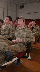 Young men in camouflage attend auditorium event