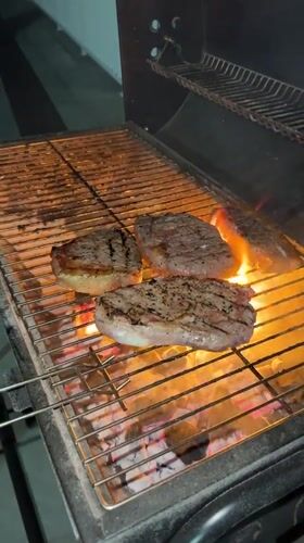 Late-night balcony BBQ with steaks over glowing coals, Bali