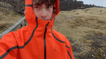 Tourist explores Icelandic boardwalks and natural landmarks in orange jacket