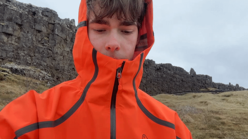 Tourist explores Icelandic boardwalks and natural landmarks in orange jacket