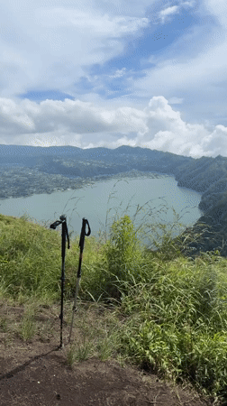 Mountain hiker documents scenic trail with lake views in Kintamani