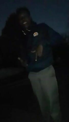 The video shows a person in a dark hooded sweatshirt and gray pants standing in what appears to be an outdoor location at night. The person's face is visible but partially obscured by the low lighting. The hoodie has a logo on the chest. They are briefly standing on what looks like a car roof.

The video then transitions to show a close-up of the person's feet. They are wearing white high-top sneakers with colored drawings on them, including a star. The sneakers are paired with green pants. The shoes are worn on pavement. The video ends with a close-up of the sneakers.