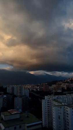 Caracas skyline at golden hour, mountains and storm clouds