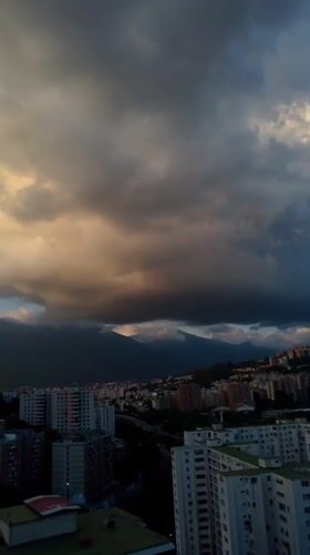 Caracas skyline at golden hour, mountains and storm clouds