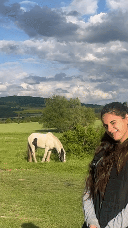Woman observed in pastoral field with grazing animals in Bulgaria