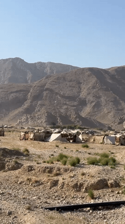 Tent encampment stretches across arid mountain terrain near Mastung