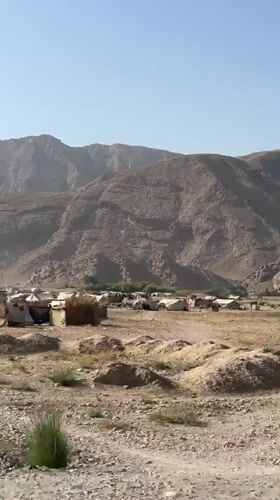 Tent encampment stretches across arid mountain terrain near Mastung