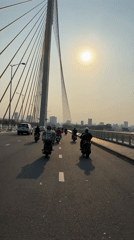 Motorcyclists cross cable-stayed bridge in Da Nang under bright sun