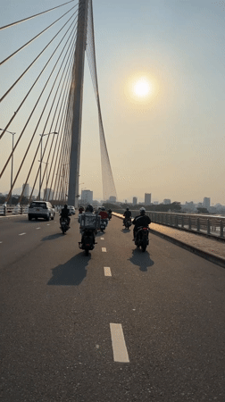 Motorcyclists cross cable-stayed bridge in Da Nang under bright sun
