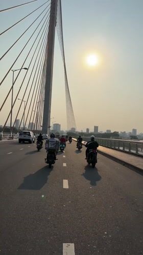 Motorcyclists cross cable-stayed bridge in Da Nang under bright sun