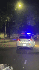Police car with emergency lights active drives through Dhaka