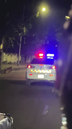 Police car with emergency lights active drives through Dhaka