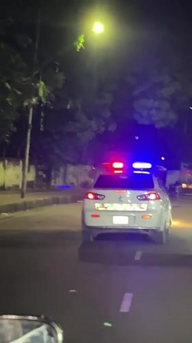 Police car with emergency lights active drives through Dhaka