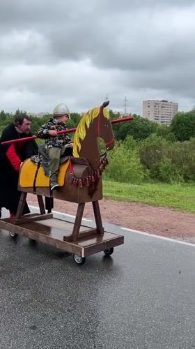 Man pushes wooden horse toy with child in Vsevolozhsk