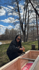 Woman paints wooden structure outdoors in Chaikovsky, Russia