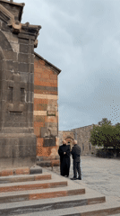 Monk meets visitor at Armenian monastery on cloudy morning