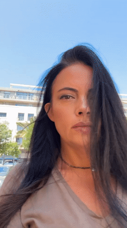 Back-to-back selfies on a Tel Aviv street, midday.