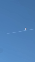 Jet contrail crosses moon over The Hague evening sky