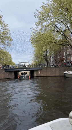 Canal boat passengers document Amsterdam waterway tour