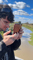 Man plays Nintendo 3DS on bridge overlooking canal