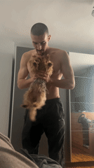 Man holds small dog in bedroom in Burgas