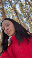 Woman in red jacket filmed smiling in pine forest