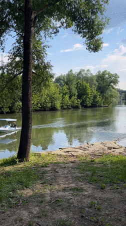 Small canopied boat glides through a lush green Russian waterway